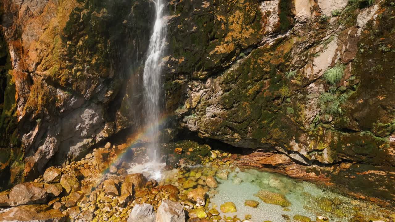 Clear mountain waterfall flowing over mossy rocks into a turquoise pool in Albania. Peaceful and natural landscape perfect for travel or nature footage