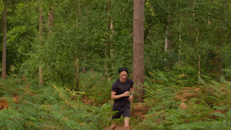 tired mid adult man exercising doing work out outdoors running along track through forest stopping to catch breath shot in real time