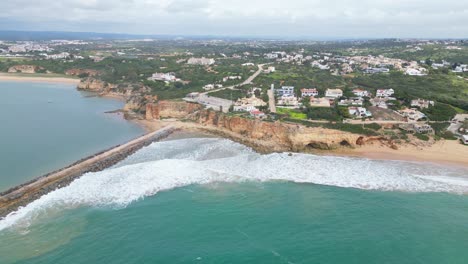 cliffside homes and ocean waves on a cloudy day in ferragudo, algarve, portugal