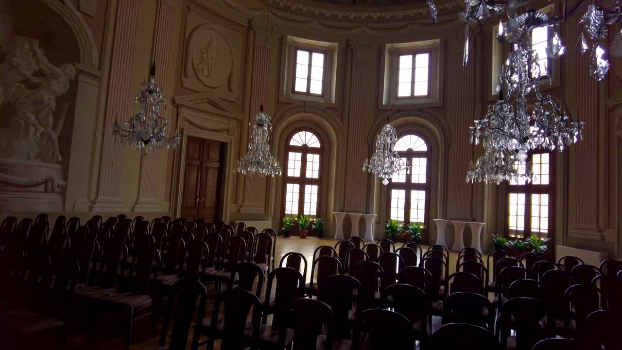 gran salón lujoso lleno de sillas y candelabros de cristal en un castillo en slavkov u brna, república checa
