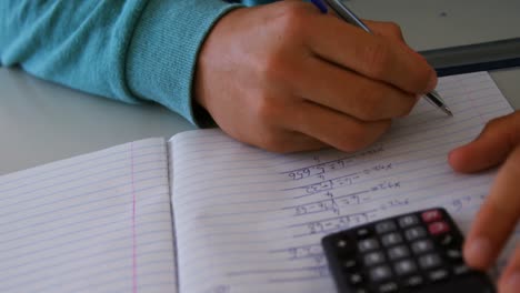 Schoolboy-doing-classwork-in-classroom