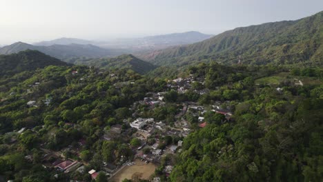 Aerial-view-of-Minca,-Colombia,-surrounded-by-lush-green-mountains-and-dense-forest