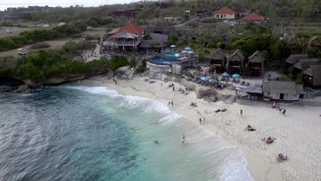 impresionante vuelo de vista aérea hundiéndose lentamente en imágenes de drones de la idílica playa de ensueño con resort frente al mar en nusa lembongan al mediodía en bali 2017