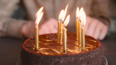 cerca de un hombre irreconocible soplando velas en el pastel de cumpleaños