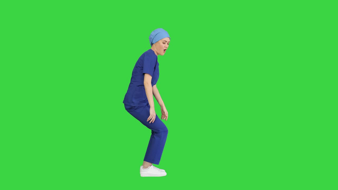 초록색 스크린, 크로마 키에 파란 유니폼을 입은 예쁜 춤추는 의사