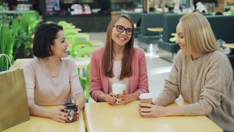 three women friends having coffee and conversation at a food court