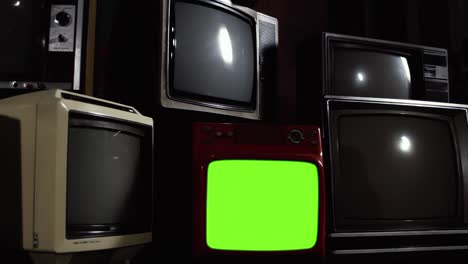 el televisor vintage se enciende en pantalla verde en medio de una pila de televisores retro. resolución 4k.