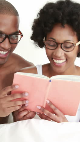 smiling young couple reading book together