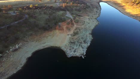 aerial drone footage captures new hogan lake’s vast waters and rugged shoreline, nestled in valley springs.