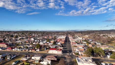 aerial footage moves steadily above a residential main street in glen innes, australia, under bright daylight with scattered clouds and clear urban layout