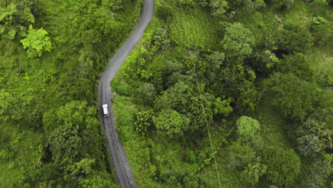 aerial of 4x4 jeep touring car driving off road crossing jungle green deep vegetation exploring costa rica