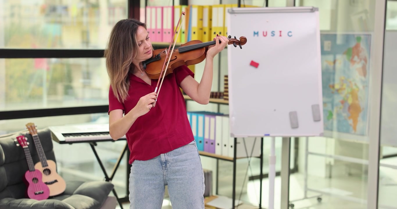 Donna suona intensamente il violino con l'archetto in mano in una stanza luminosa