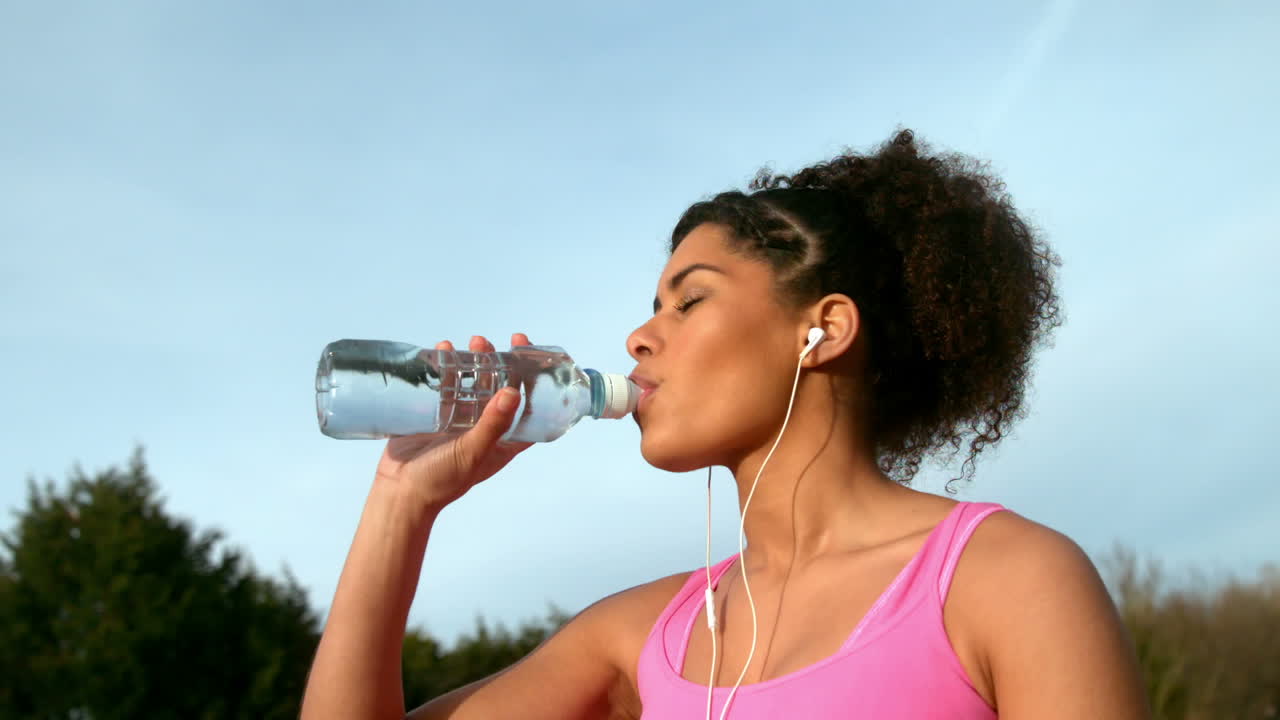 mujer en forma bebiendo agua después de correr afuera
