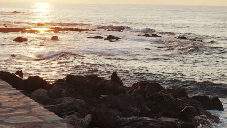 toma en cámara lenta de la puesta de sol sobre las olas del océano rompiendo contra las piedras, mar egeo chania, creta grecia