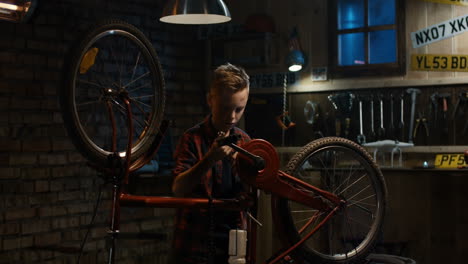 boy fixing a bicycle in a garage