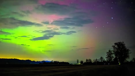 time-lapse of the vivid northern lights dancing above countryside farmlands