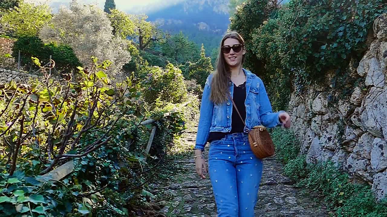 Slow motion (120fps): happy young beautiful lady walks downhill in Mallorca, Spain