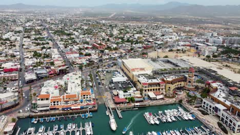 Panorámica-Con-Cámara-En-El-Aire-De-Los-Botes-De-Agua-En-El-Agua-Y-La-Ciudad-Con-Montañas-En-El-Fondo