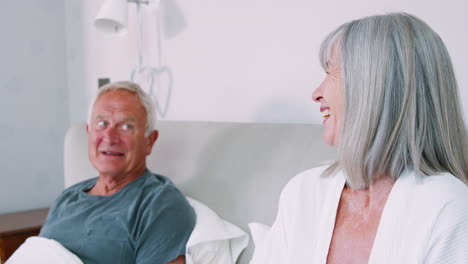 Retired-Couple-Wearing-Pajamas-Sitting-In-Bed-Drinking-Tea