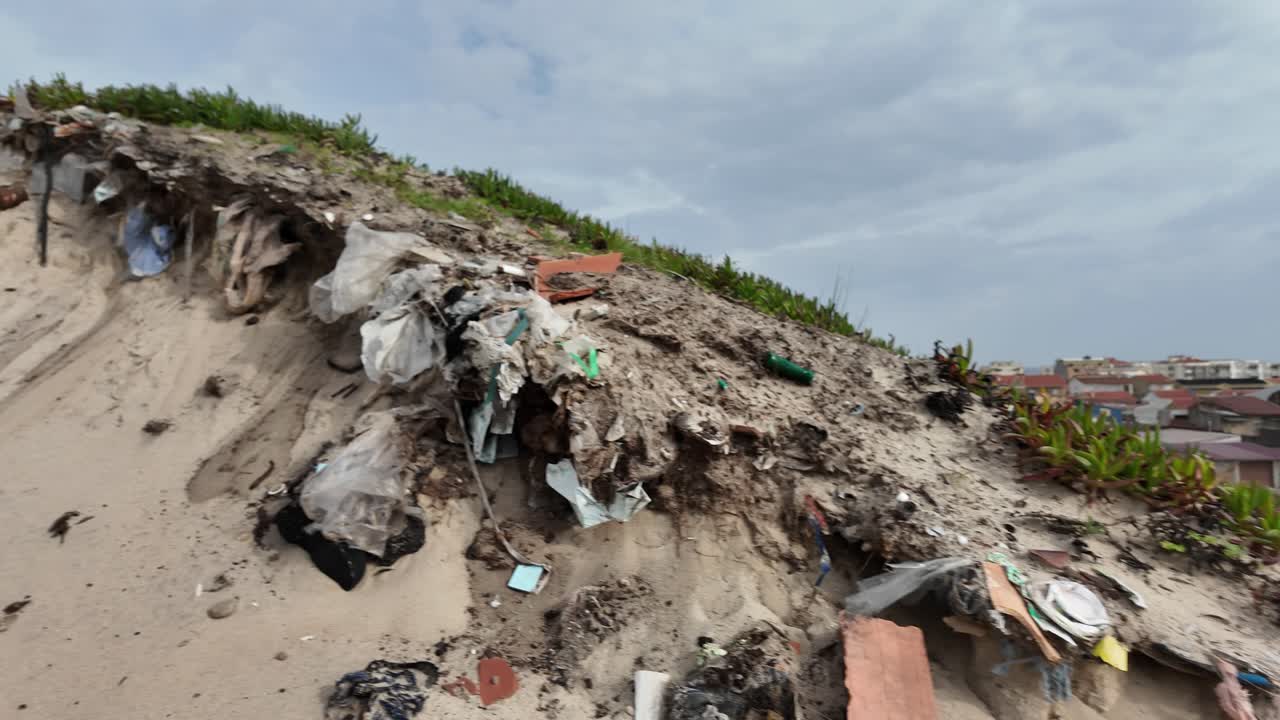 Buried trash on the sand dunes in coastline in Portugal. Ocean plastic. Beach trash