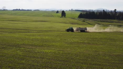 tractor agrícola con cargador grande conduciendo por caminos de tierra creando polvo, colinas verdes, antena