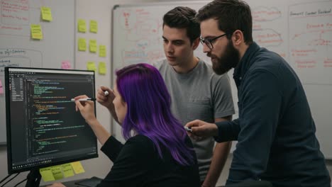 a collaborative coding session where three individuals engage in a problem-solving discussion, highlighting teamwork and creativity in a tech environment with vivid post-it notes
