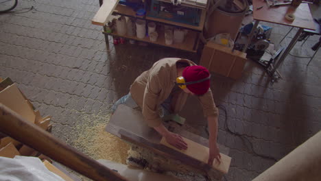 top down of carpenter planing wooden plank in workshop