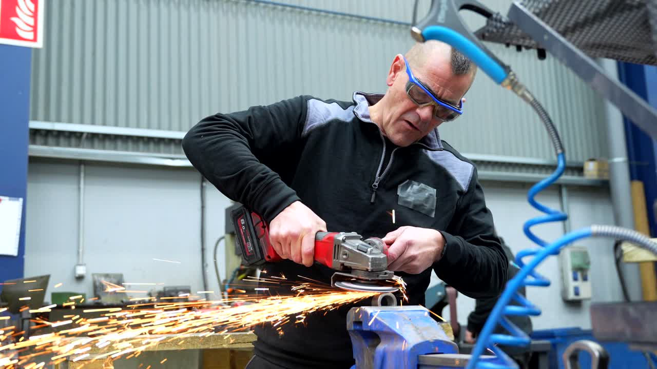 Man grinding metal with angle grinder in workshop