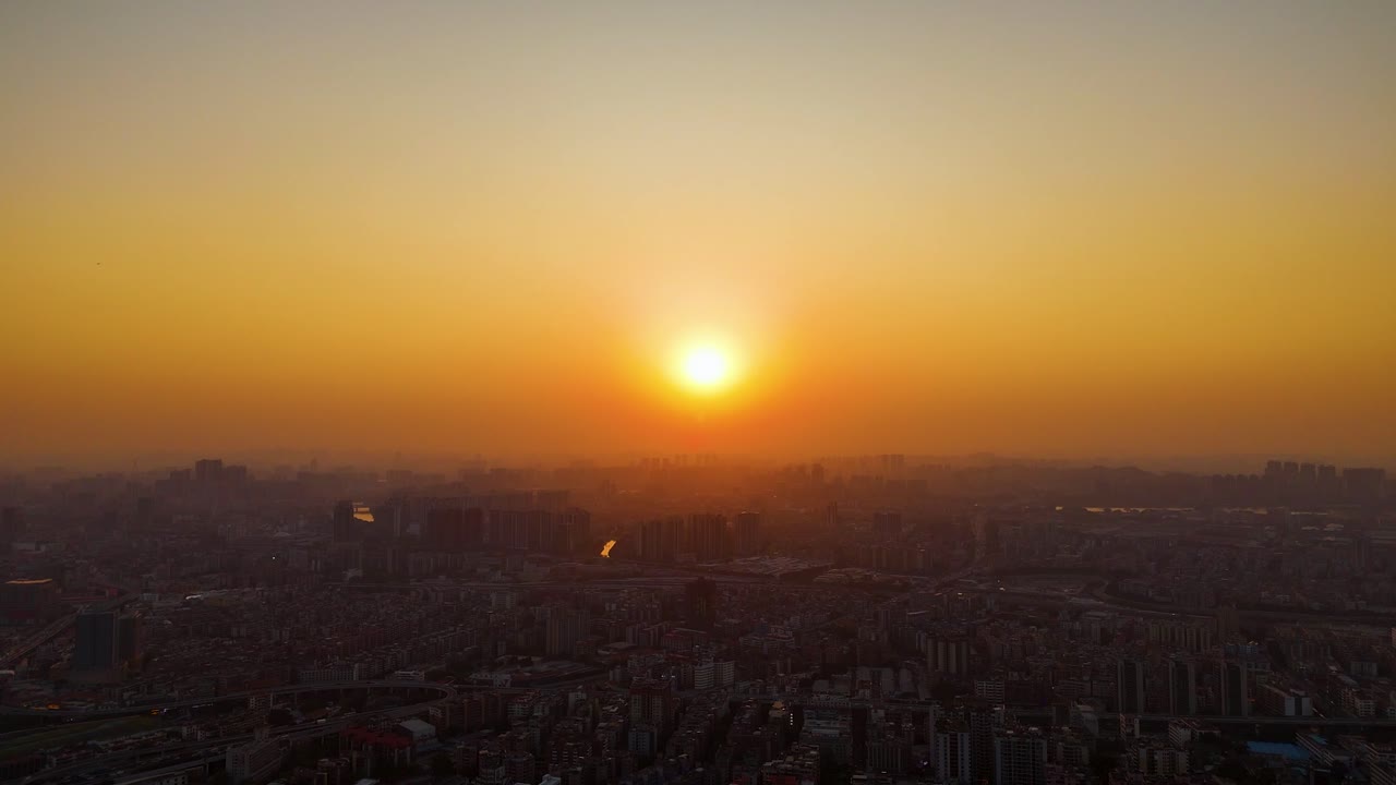 Aerial view of Guangzhou cityscape at sunset, capturing the golden hues of the sky over the sprawling urban landscape, with the sun setting behind the city’s edge. China