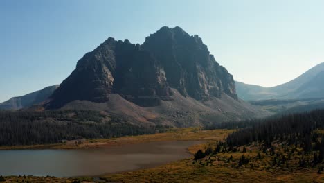 Stunning-aerial-drone-landscape-nature-trucking-left-shot-of-a-large-meadow-with-a-small-stream-with-the-beautiful-Lower-Red-Castle-Lake-and-peak-behind-up-in-the-High-Uinta-national-forest-in-Utah