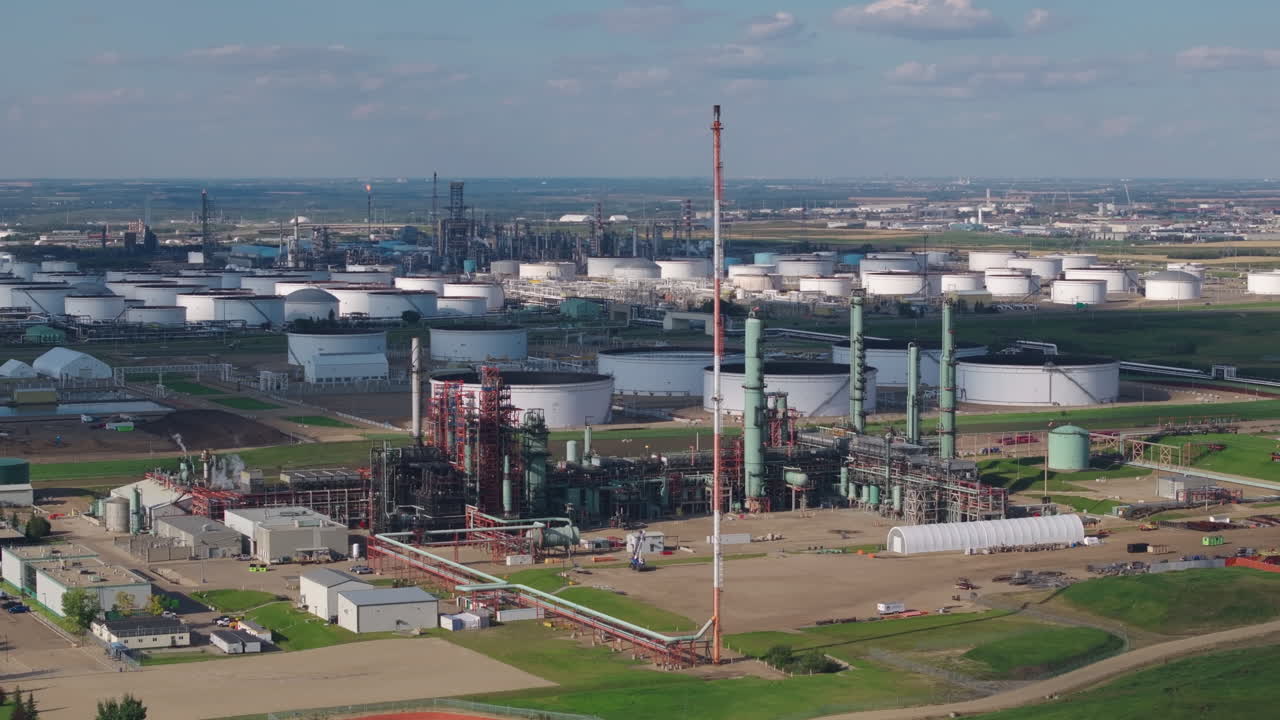 Industrial plant landscape with tanks, chimneys, and cloudy sky