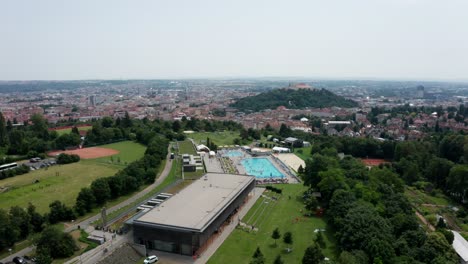 right side drone shot of public outdoor swimming pool and castle in brno city