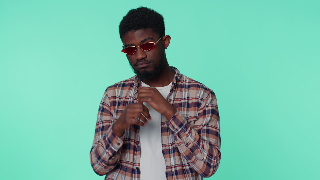 Seductive cheerful stylish african american man wearing sunglasses, charming smile on gray wall