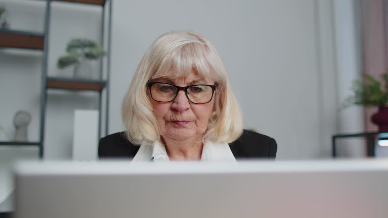 Senior business woman freelancer using laptop computer sits at workplace typing browsing at office
