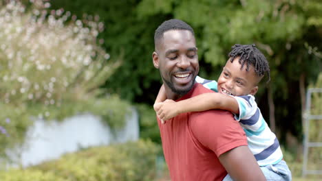 Afroamerikanischer-Vater-Lässt-Seinen-Sohn-Huckepack-In-Einem-Sonnigen-Park-Zu-Hause-Mit-Kopierraum-Fahren