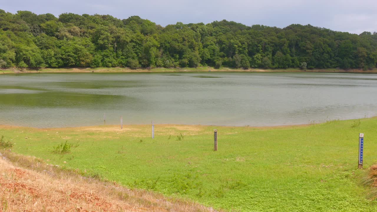 Explore a serene water dam nestled in verdant landscapes. The calm waters and surrounding trees create a tranquil mood, perfect for nature lovers and outdoor enthusiasts seeking relaxation