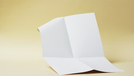 Video-of-piece-of-white-paper-with-creases-on-yellow-background