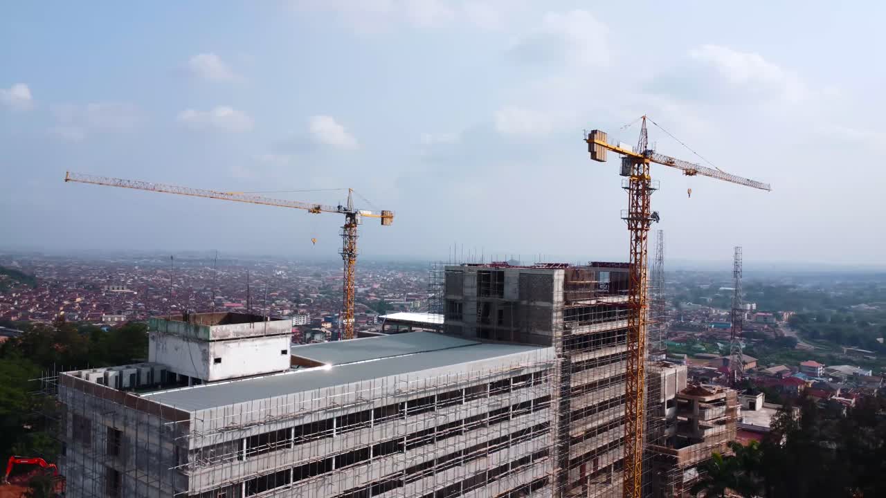 Aerial pullback from Mokola Hill hotel site showing cranes and pigeons above rooftops. Drone captures a beautiful hawk fly near Premier Hotel reconstruction, Ibadan, Nigeria