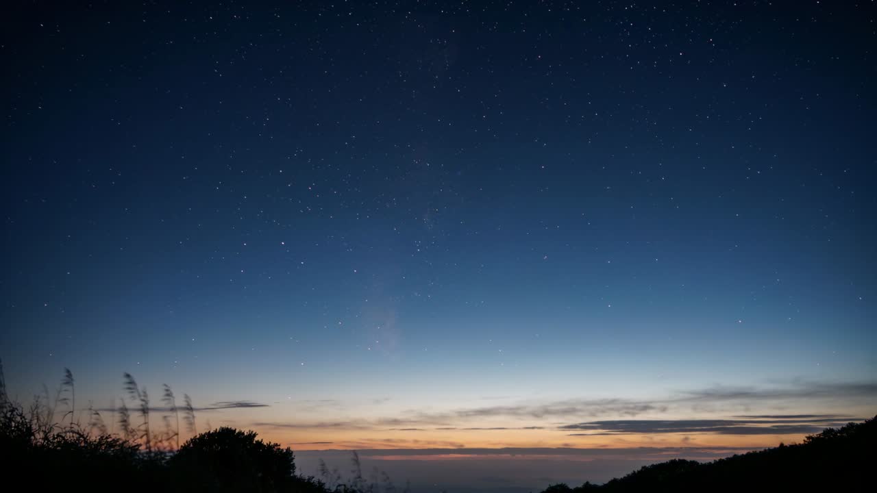 夜晚轉為黎明的天空，星星漸暗，同時照亮山丘上的垂直光帶，伴隨日出
