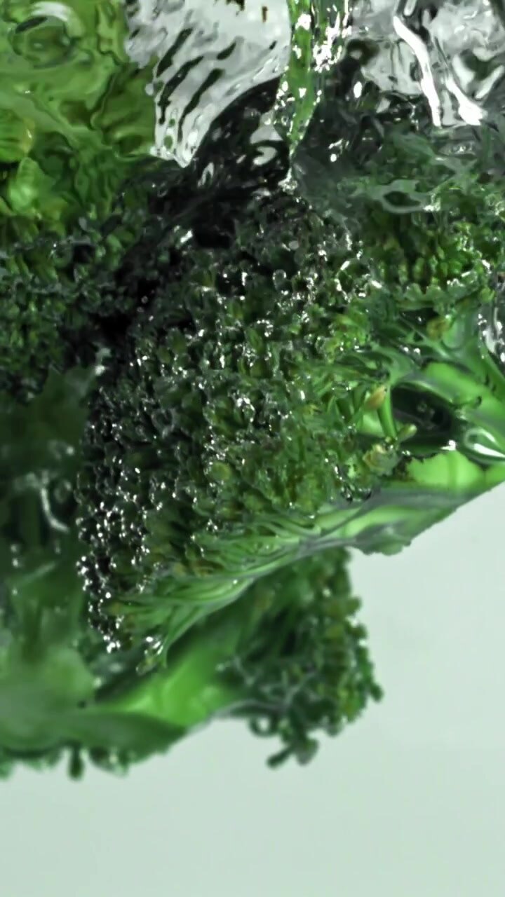 Cimette di broccoli verdi freschi che si immergono nell'acqua al rallentatore