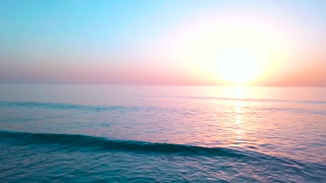 Spectacular-magical-dramatic-golden-sunset-over-ocean,-breaking-waves-reveal-setting-sun-on-the-horizon-Beautiful-tropical-background---Low-aerial