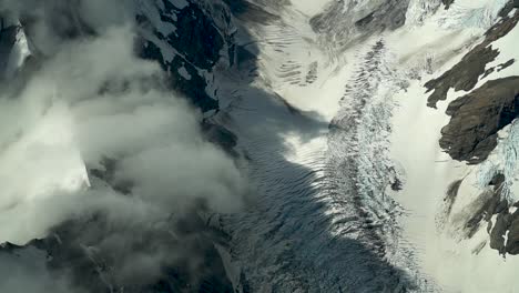 slowmo - hooker glacier, southern alps, new zealand with clouds, snow and rocky mountains from scenic airplane flight