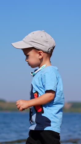 small infant boy playing on a beach. summer playing on sunny day. vertical video