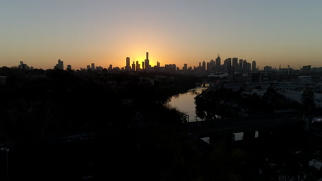 aerial shot along yarra river in expensive suburb in melbourne, australia, with the silhouette city on the horizon, drone.