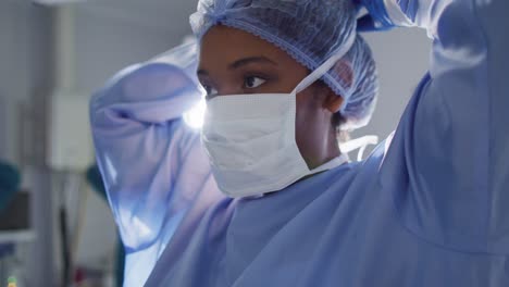 Video-of-african-american-female-surgeon-tying-face-mask-in-operating-theatre