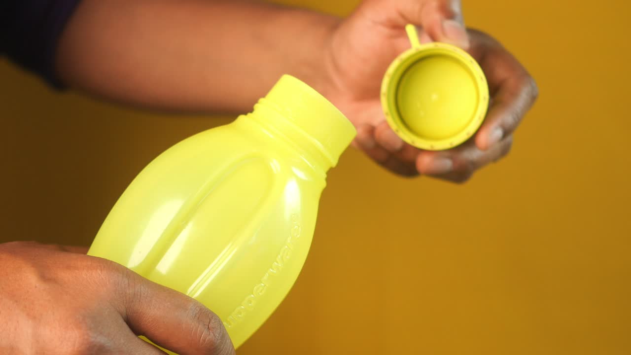 Person opening a yellow plastic water bottle
