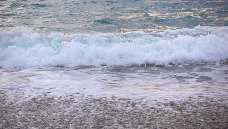 una foto de cerca de las olas del océano en cámara lenta sobre una playa de guijarros en la bahía de looc, filipinas