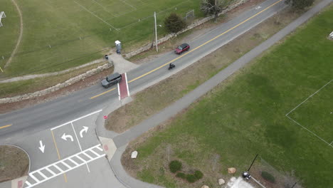 drone sigue la toma de una motocicleta saliendo de un estacionamiento y conduciendo por la carretera