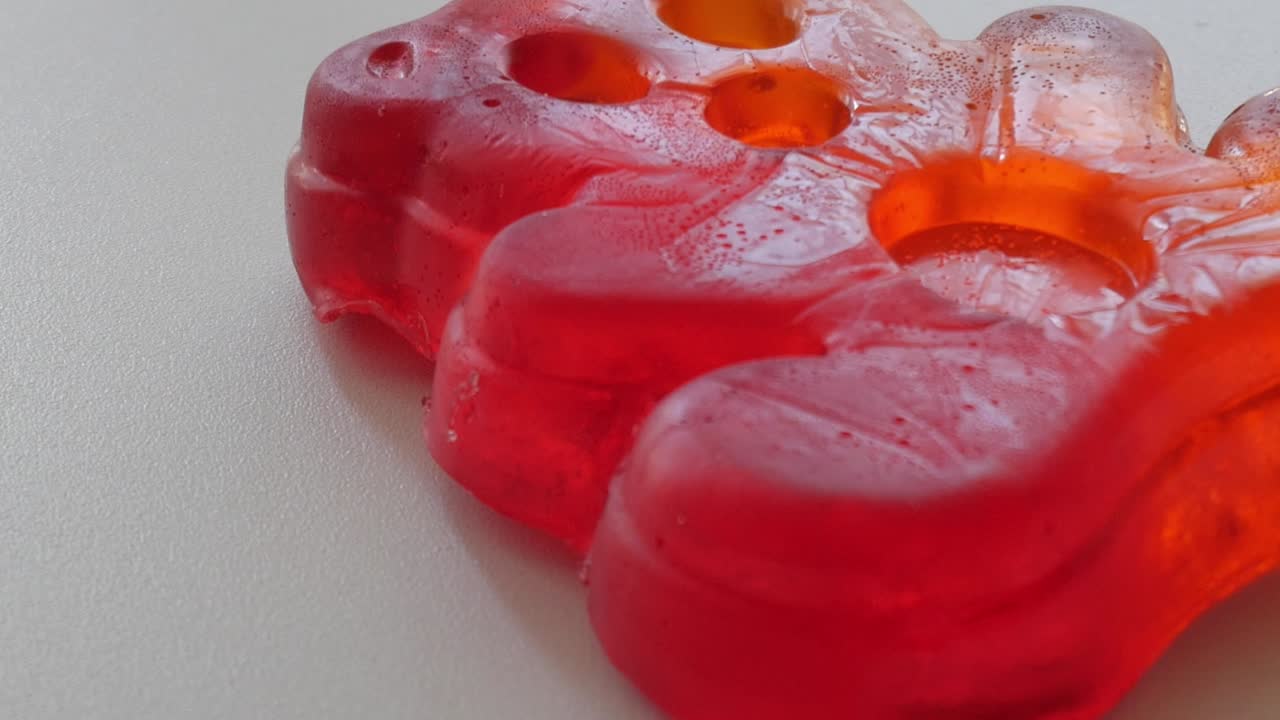 Close-up of red gummy candy with sunlight reflections on a table