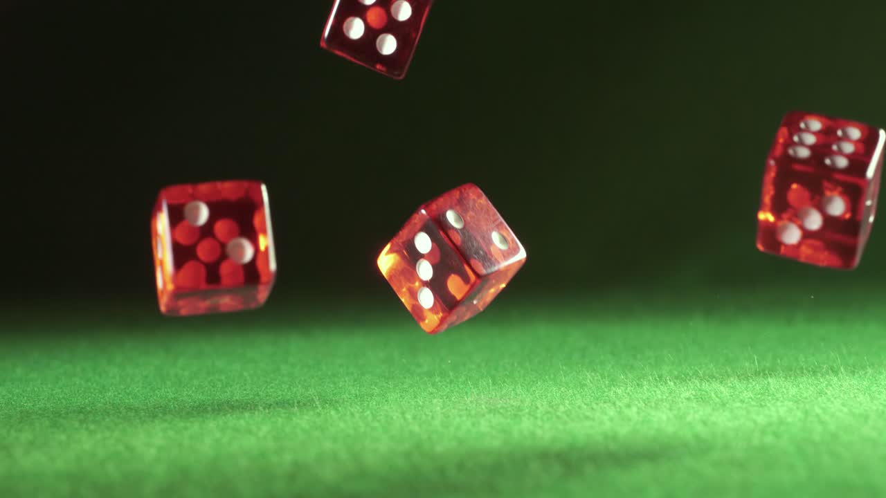 los dados rojos caen y rebotan en la mesa verde sobre un fondo oscuro. filmado con una cámara súper lenta de 1000 fps.